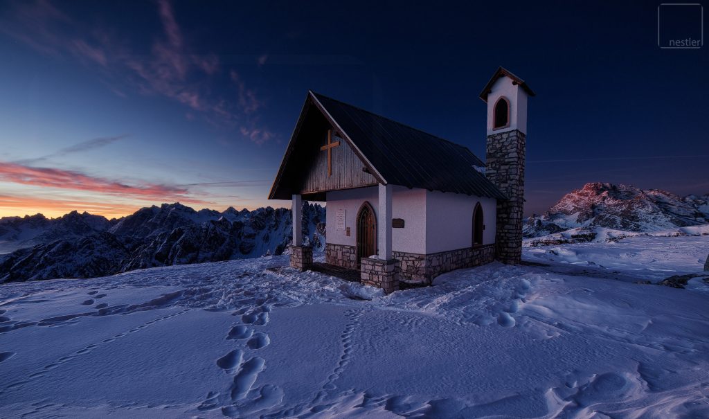 A chapel in the mountains at sunrise in the Italian Dolomites in Winter